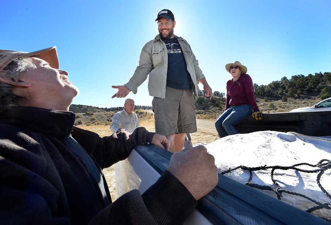 (Scott Sommerdorf   |  The Salt Lake Tribune)   
Paleontologists Alan Titus, left and Tylor Birthisel, center, laugh as they work to position one of the plaster-encased bundles of the fossilized Tyrannosaurus Rex skeleton found near Tropic, Utah, Sunday, October 15, 2017. The collected pieces of the animals' skeleton were airlifted to this site from the site where the skeleton was found in 2015 by Titus.