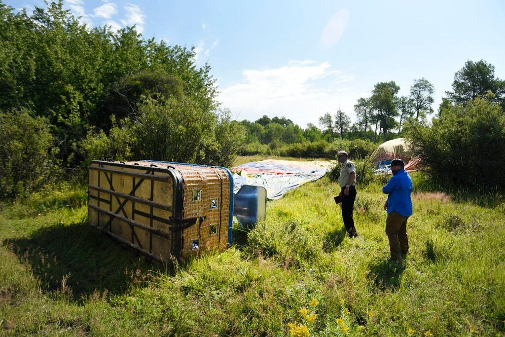 (Bradly J. Boner | Jackson Hole News&Guide via AP, file) In this Monday, Aug. 3, 2020 photo, Teton County Sheriff Matt Carr and Investigative Sgt. Clay Platt examine the southernmost of three balloons that crashed during a flight near Teton Village, Wyoming. The owner of a Wyoming sightseeing balloon company says a downdraft during a freak storm caused three hot air balloons to crash this week. Monday's crashes injured more than a dozen people, including 11 who went to hospitals.