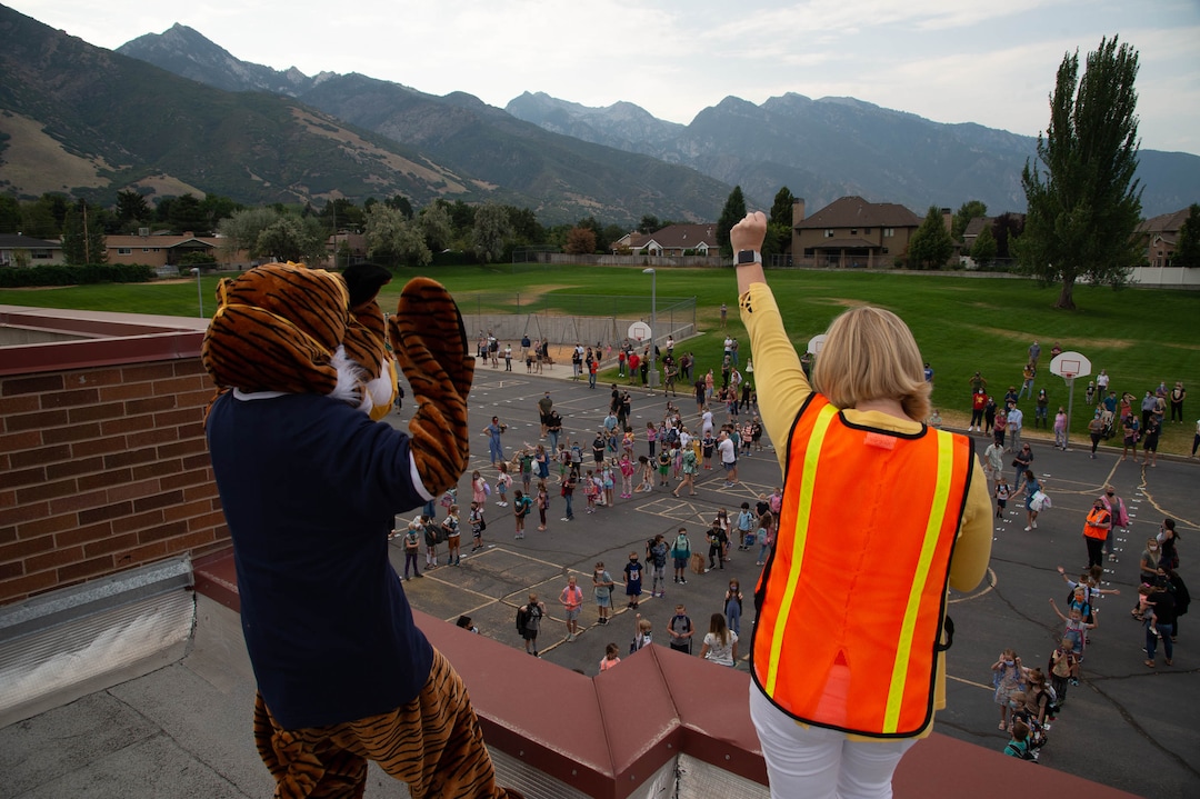 (Francisco Kjolseth  |  The Salt Lake Tribune)  Home of the Cubs, Canyon View Elementary school mascot Bennie, played by PTA president Emily Weigel waves to kids as school principal Kierstin Draper uses a megaphone to greet students back from the roof of the school. It was the first day of classes for the Canyons School District on Monday, August 24, 2020.