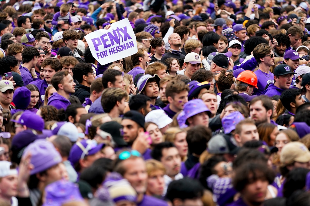(Lindsey Wasson | AP) A fan holds a sign for Washington quarterback Michael Penix Jr. to receive the Heisman trophy following Washington's 36-33 victory over Oregon on Saturday in Seattle.