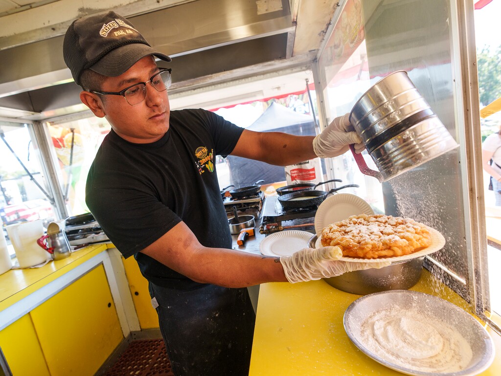 (Leah Hogsten | The Salt Lake Tribune) Gerardo Romero Hernandez with Funnel Cakes West sprinkles powdered sugar onto a golden brown funnel cake at the Utah State Fair, Sept. 9, 2022. The 2023 edition of the Utah State Fair runs Sept. 7-17, 2023, at the Utah State Fairpark.