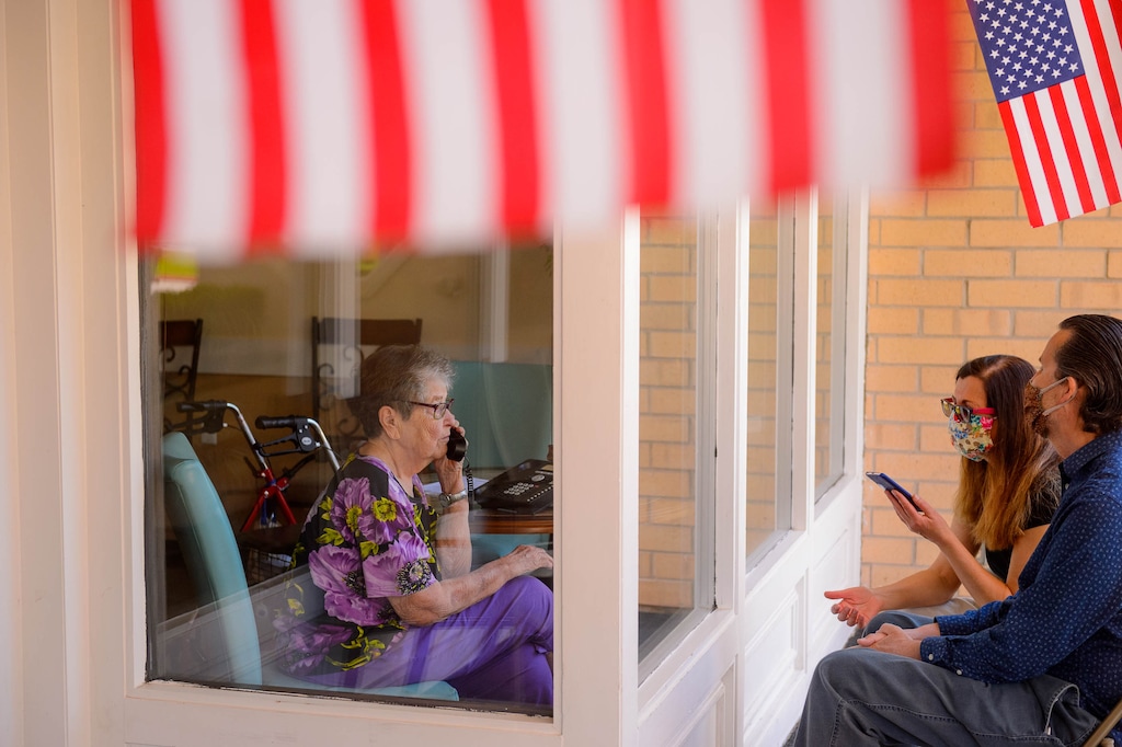 (Trent Nelson  |  The Salt Lake Tribune) 99-year-old Audrey B. Carr visits with her son, Harold, and daughter-in law, Flavia Cervino-Wood, through the front window at Heritage Place Senior Living in Bountiful on Friday, June 19, 2020.