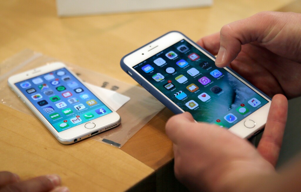 FILE - A Friday, Sept. 16, 2016 file photo of a customer setting up his new iPhone 7 Plus, right, as he switches from the iPhone 6 at the Apple Store on Michigan Avenue, Chicago, IL., during the release of the Apple iPhone 7. (AP Photo/Kiichiro Sato, File)