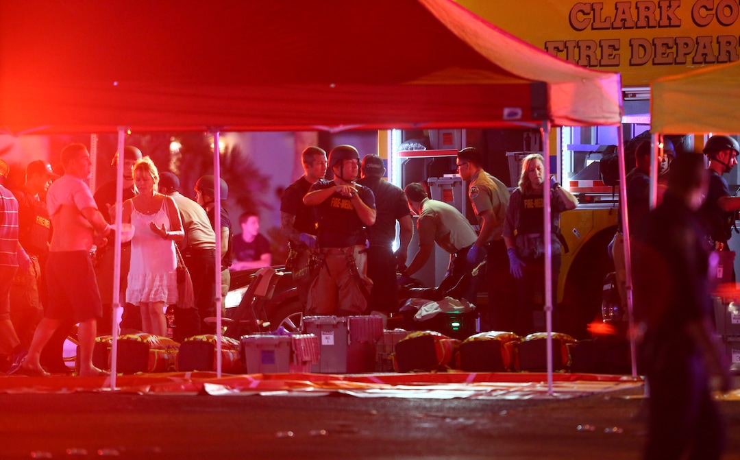 Medics treat the wounded as Las Vegas police respond during an active shooter situation on the Las Vegas Stirp in Las Vegas Sunday, Oct. 1, 2017. Multiple victims were being transported to hospitals after a shooting late Sunday at a music festival on the Las Vegas Strip. (Chase Stevens/Las Vegas Review-Journal via AP)