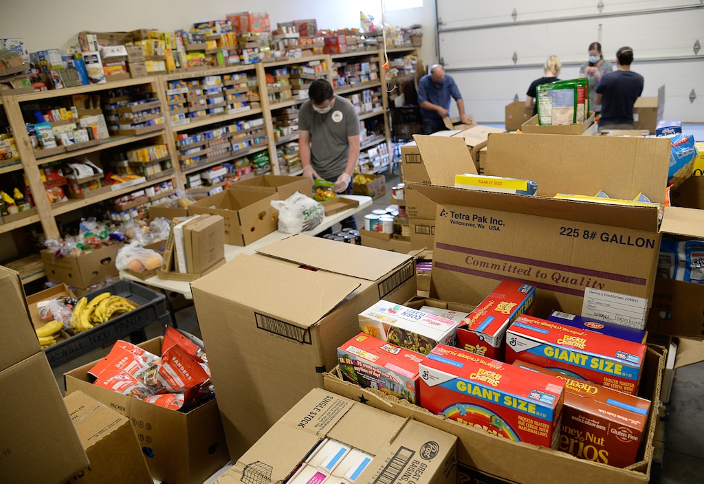 (Francisco Kjolseth  |  Tribune file photo) Volunteers sort through food at the Taylorsville Food Pantry on Saturday, May 30, as people line up outside.