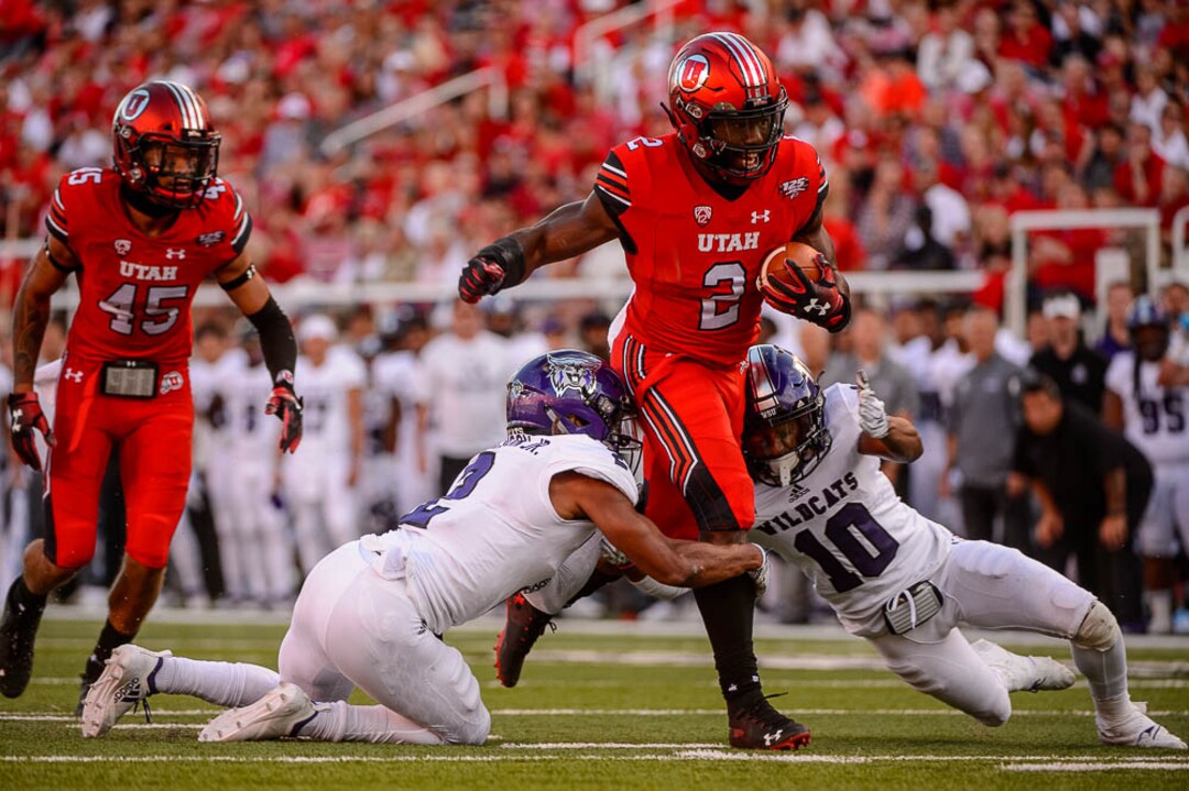 (Trent Nelson | The Salt Lake Tribune)  Utah Utes running back Zack Moss (2) runs between Weber State Wildcats safety Jawian Harrison Jr. (2) and Weber State Wildcats cornerback Keilan Benjamin (10) as the University of Utah Utes host the Weber State Wildcats, Thursday Aug. 30, 2018 at Rice-Eccles Stadium in Salt Lake City.