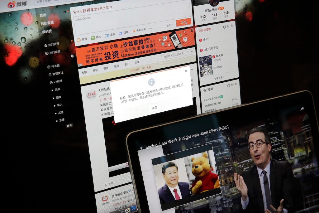 A screen shows a failure message saying a post could not be sent because "the content contains information that violates relevant laws and regulations" on Sina Weibo next to a smaller computer screen showing a "Last Week Tonight" HBO show's host John Oliver with a photo of Chinese President Xi Jinping and Winnie the Pooh, in Beijing, Friday, June 22, 2018. The popular Chinese social media site is blocking users from posting about the show and its HBO host Oliver after the news satire program aired a segment this week making fun of Xi. (AP Photo/Andy Wong)