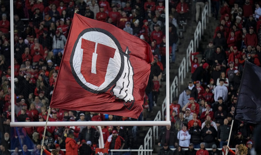 (Bethany Baker  |  The Salt Lake Tribune) A man runs with the Utah Utes flag during the game at Rice-Eccles Stadium during a game in 2024.