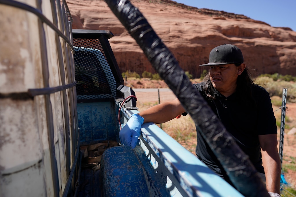 (Carolyn Kaste | AP file photo) Chris Topher Chee waits for water to fill a tank in the back of his truck to haul home in Oljato-Monument Valley, Utah, on the Navajo Nation on April 27, 2020.