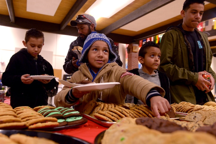 (Leah Hogsten  |  The Salt Lake Tribune) l-r Lissandro Cervantes-Magana (center) points to the cookie he desires as his brother Imanol, 11, and father Agustin (left) wait in line. At right is Joel Seranno and his brother Oscar, 13, who attends seventh grade at Granite Park Junior High. Sixteen members of Granite Park Junior High SchoolÕs faculty prepared and served a hot spaghetti meal to students and their families, Friday, December 22, 2017 at the school for the inaugural ÔDinner at the Park.' Roughly 90 percent of students who attend Granite Park Junior High in South Salt Lake qualify for free or reduced lunch through the federal school lunch program. Knowing the challenges faced by their students, staff members at Granite Park came up with an idea to help families through the holidays.