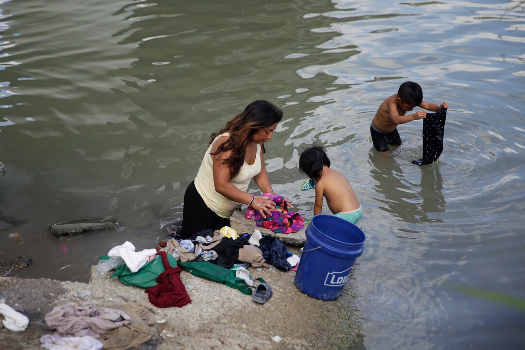 In this Wednesday, Nov. 6, 2019, migrants living in a refugee camp across from Brownsville, Texas, in Matamoros, Mexico, wash cloths in the Rio Grande. Some people bathe and wash their clothes in the Rio Grande, known to be contaminated with E. coli and other bacteria. (AP Photo/Eric Gay)