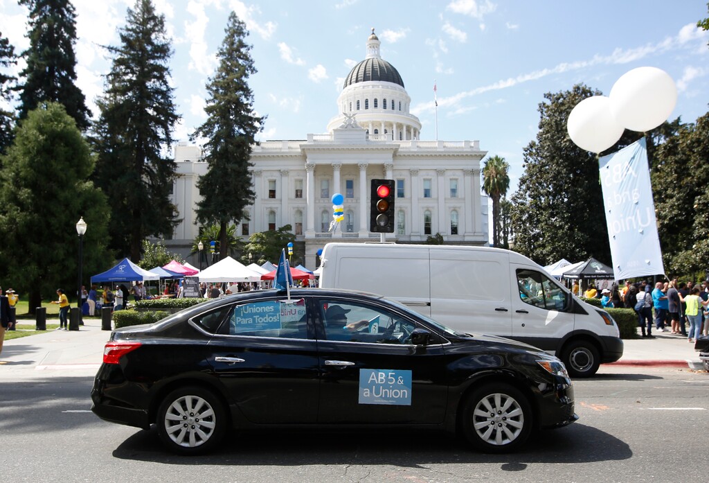 (Rich Pedroncelli | AP file photo) In this Aug. 28, 2019 file photo supporters of a measure to limit when companies can label workers as independent contractors circle the Capitol during a rally in Sacramento, Calif. Gov. Gavin Newsom signed a measure, to take effect in 2020, making it harder for industries to treat workers like contractors instead of employees who are entitled to minimum wage and other benefits. Uber, Lyft and DoorDash have said they'll spend $30 million to put an initiative on the 2020 ballot to overturn the law.