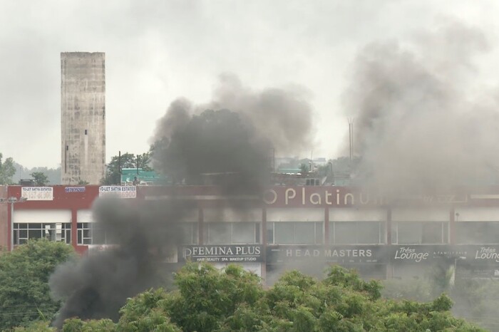 In this image made from video, smoke rises as supporters of an Indian guru who calls himself Saint Dr. Gurmeet Ram Rahim Singh Ji Insaan react after his verdict was announced in Panchkula, India, Friday, Aug. 25, 2017. A north Indian court convicted the flamboyant leader of a quasi-religious sect of raping two of his followers, prompting thousands of supporters to shout angry protests and attack journalists covering Friday's verdict. (AP Photo)