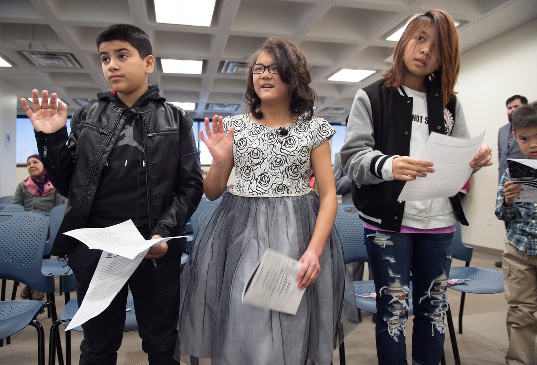 (Scott Sommerdorf   |  The Salt Lake Tribune)   Haitham Layth Mohammed Ali, left, Lachlan Murray, and Diana Vo, right, take the citizenship pledge during a ceremony in recognition of children who have obtained citizenship through their parents, Thursday, December 28, 2017. Some were adopted by U.S. citizen parents; others derived citizenship when their immigrant parents became naturalized citizens.