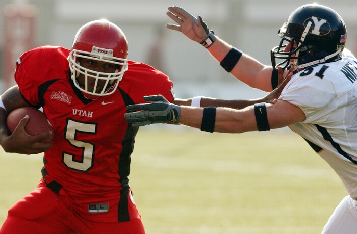 (Tribune File Photo)  Utah's  Brandon Warfield gives the stiff arm to BYU's #31 Kip Nielsen during the rivalry game on November 23, 2002. 