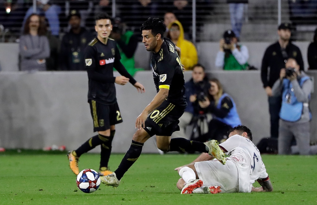 Los Angeles FC's Carlos Vela, center, leaps over Real Salt Lake's Kyle Beckerman during the second half of an MLS soccer match Saturday, March 23, 2019, in Los Angeles. (AP Photo/Marcio Jose Sanchez)