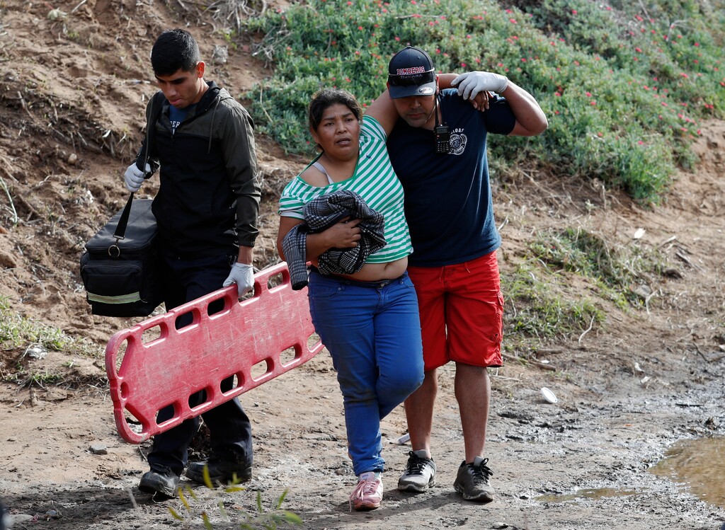 (Rebecca Blackwell | The Associated Press) Honduran migrant Helda Lainez, 38, is helped by Mexican first responders after falling from the U.S. border wall and hurting her ankle while trying to cross, in Tijuana, Mexico, Sunday, Dec. 9, 2018. After falling, Lainez was unable to make it over the wall, and her 3-year-old and 1-year-old children who had crossed before her were taken into custody by the Border Patrol.