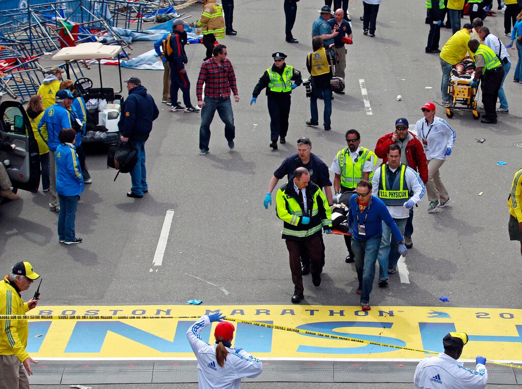 (Charles Krupa | The Associated Press) In this April 15, 2013 file photo, medical workers wheel injured victims across the finish line after a nearby bombing during the Boston Marathon in Boston. The world premiere of "Finish Line," a documentary stage play about the bombing, is set to open on Wednesday, March 15, 2017, in Boston.