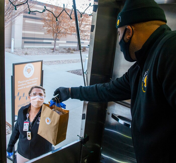 (Rick Egan | The Salt Lake Tribune)  Sid Burgos hands a bag of grilled cheese sandwiches to Sharlene Heward, to be delivered to 600 health care workers as part of the the Curds + Kindness program, which supports local dairy farmers, at the South Jordan Health Center in Daybreak on Tuesday, Dec. 1, 2020.