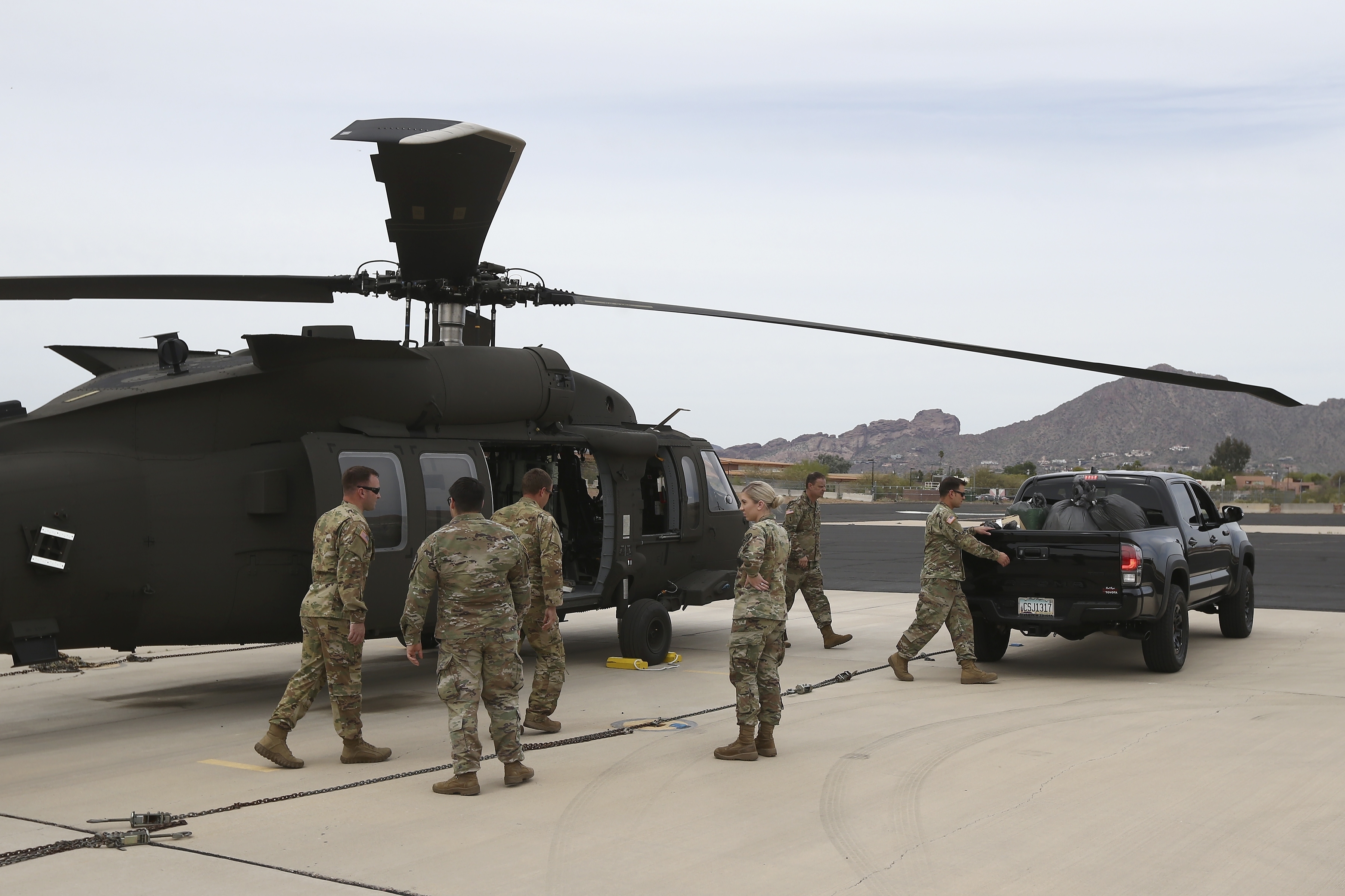 (Ross D. Franklin | AP) Members of an Arizona National Guard unit pause while loading a helicopter with medical supplies to be taken to the remote Navajo Nation town of Kayenta, Tuesday, March 31, 2020, in Phoenix. The reservation has been hard-hit by the coronavirus.