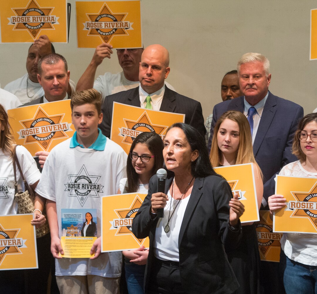 (Rick Egan  |  The Salt Lake Tribune)  Rosie Rivera gives a second speech Saturday, Aug. 12, 2017, before the final vote for Salt Lake County sheriff. Fellow candidates Levi Hughes, Fred Ross, Ken Hansen — who lost in the previous round — hold signs supporting her.