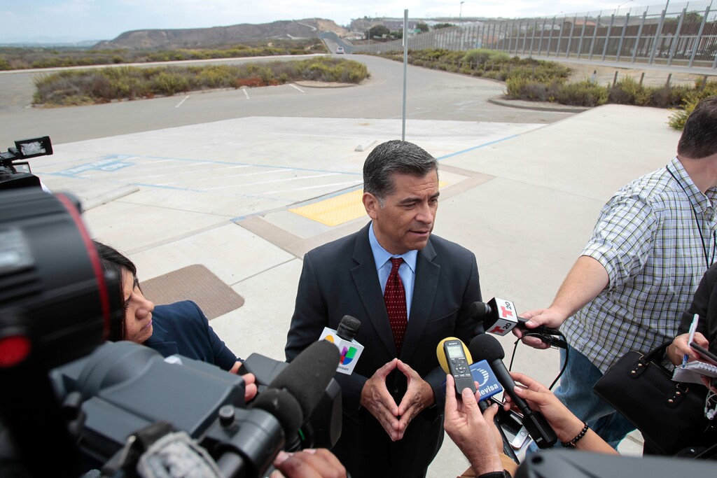With the U.S Mexican border in the background, California State Attorney General Xavier Becerra talks to members of the media after he announced that he'd be filing a lawsuit against the Trump administration over the building of a wall on the U.S. border with Mexico, during a news conference at Border Field State Park in San Diego on Wednesday,  Sept. 20, 2017. (Hayne Palmour IV/The San Diego Union-Tribune via AP)