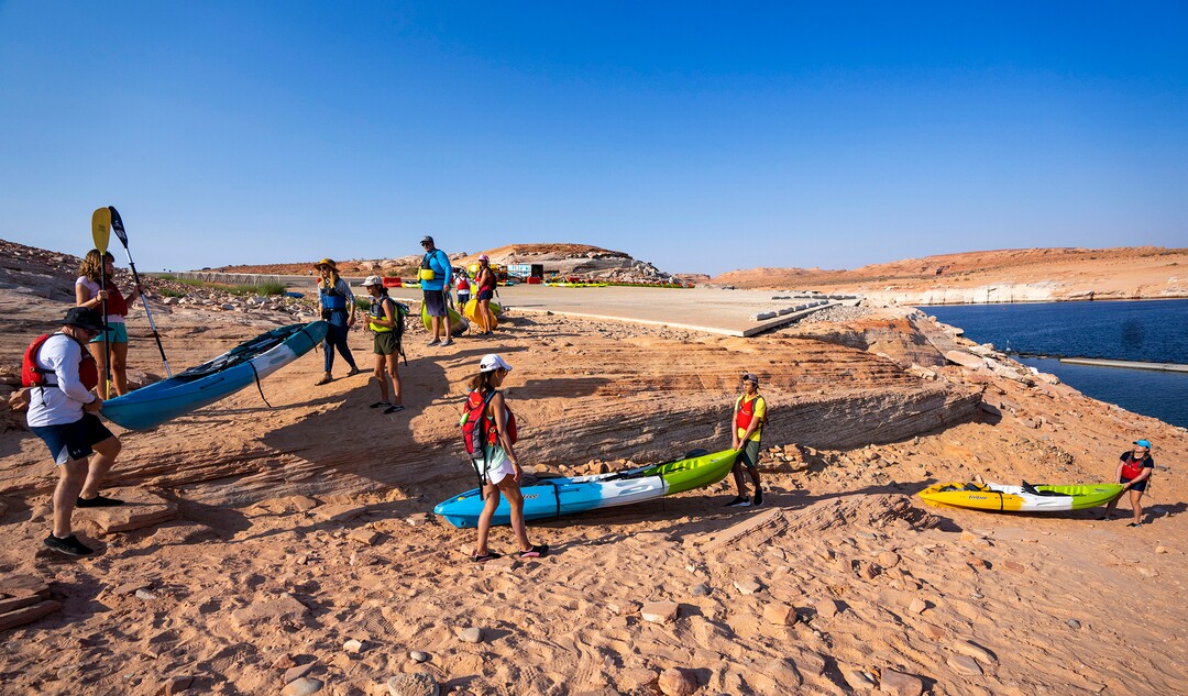 (Rick Egan | The Salt Lake Tribune) Due to the low water levels, Kayakers have to haul their kayaks another 30-50 yards to the water past the abandoned Antelope Public Launch Ramp, at Lake Powell, on Wednesday, Aug. 4, 2021. Water levels are dropping a few inches a day, which may bring an early end to kayaking on the lake in the next week or so, shortening a season that usually goes through the end of October.