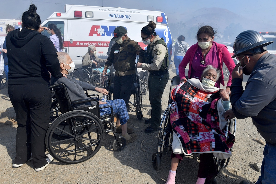(Will Lester | The Orange County Register via AP) Elderly residents of the Riverside Heights Healthcare Center in Jurupa Valley are evacuated from their care facility as flames and smoke from the Hill Fire approach Wednesday, Oct 30, 2019.