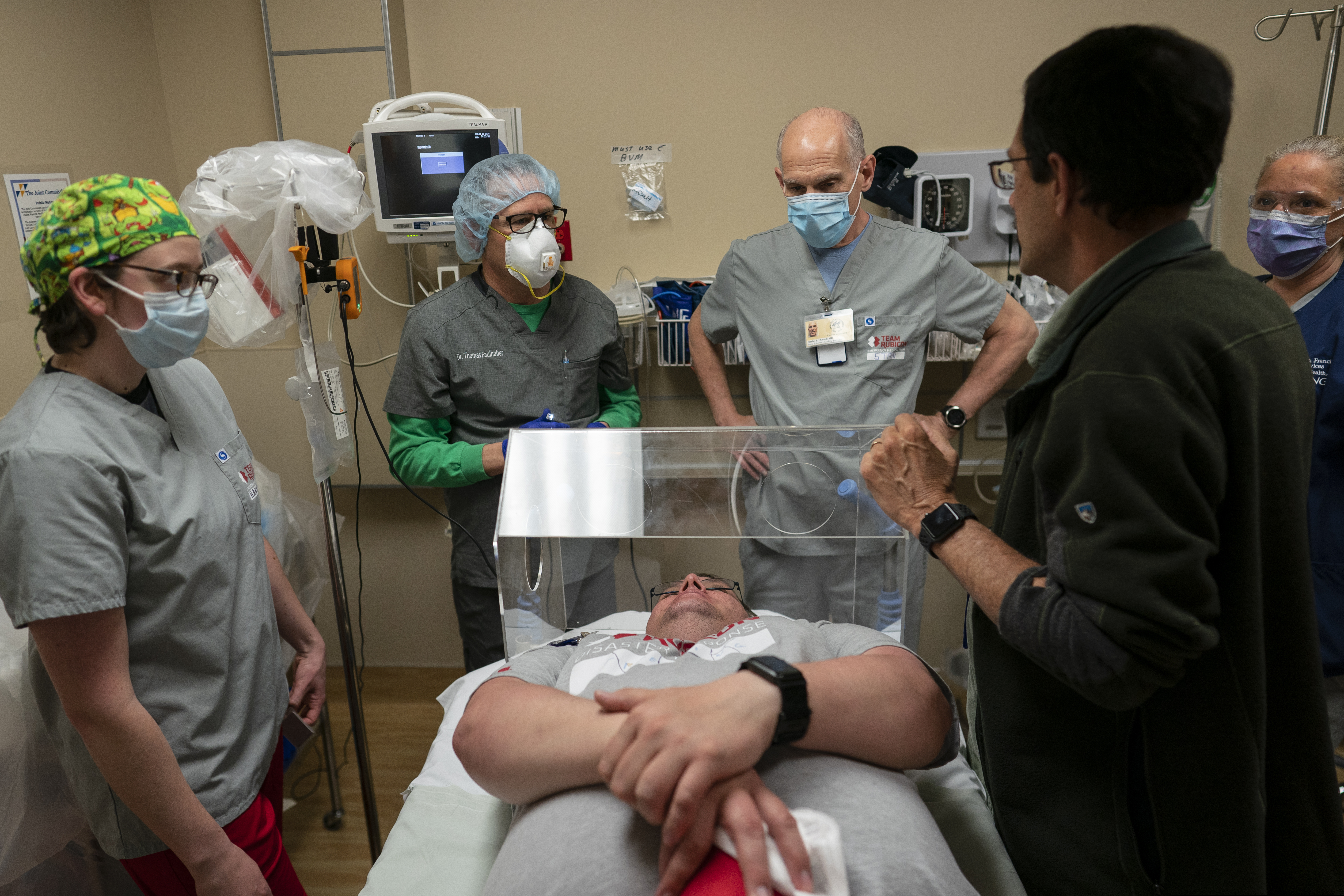 Kayenta Health Center emergency room director Dr. Anthony Griffy, second from right, works with Team Rubicon volunteers, Dr. Stan Chartoff, with the U.S. Air Force Reserve from Hartford, Conn., third from right, EMT Hannah Tellier from Boston, left and Cindy Robison, a U.S. Air Force veteran and nurse from Colorado Springs, Colo., right, as they practice with a new intubation shield that just arrived to help protect medical workers at the Kayenta Health Center emergency room Kayenta, Ariz., on  April 23, 2020. Assisting the medial staff on the table, posing as a patient, is Team Rubicon safety officer and EMT Vick Dempsey. When used, the shield is placed over the coronavirus patient's head during intubation, inserting a tube down a sedated patient's throat to give them oxygen. (AP Photo/Carolyn Kaster)