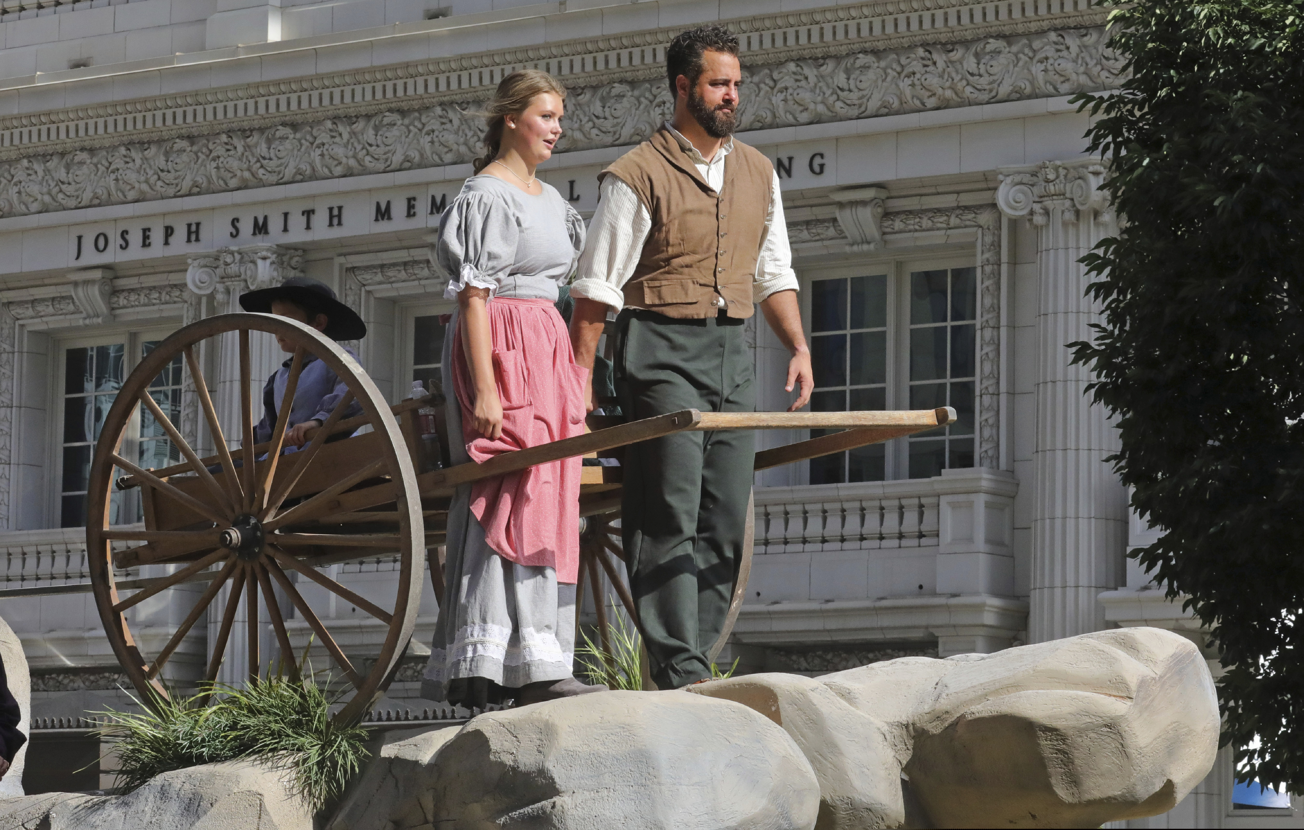 A couple rides on a float with a handcart during the Pioneer Day Parade Wednesday, July 24, 2019, in Salt Lake City. Pioneer Day is a beloved only-in-Utah holiday every July 24 that features parades, rodeos, fireworks and more. It marks the date in 1847 when Brigham Young and other Mormon pioneers, many pulling handcarts, ended their treacherous journey across the country from Illinois and discovered the Salt Lake Valley. (AP Photo/Rick Bowmer)