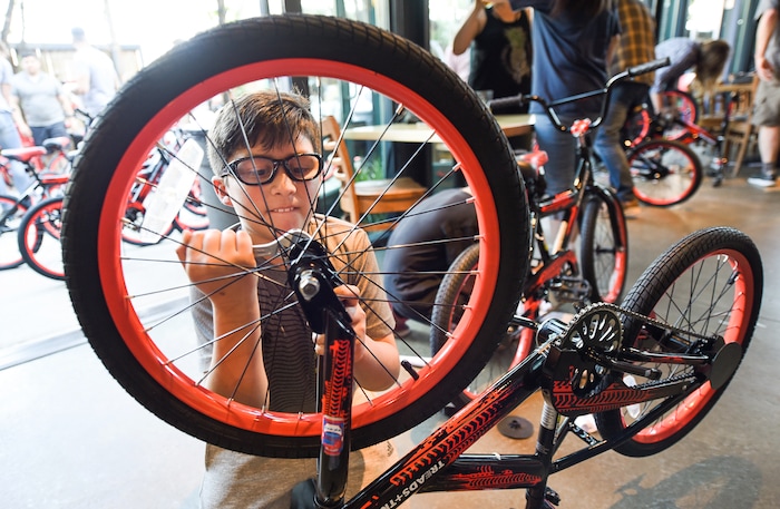 (Francisco Kjolseth  |  The Salt Lake Tribune)  Diego Fernandez, 10, puts some effort into it as he joins other volunteers and workers at Squatter's Pub Brewery to assemble 80 bicycles on Tuesday, May 29, 2018, at the brewery which will be given away to 1st and 2nd graders at Washington Elementary on Wednesday. Part of the program is backed by the Can'd Aid Foundation.