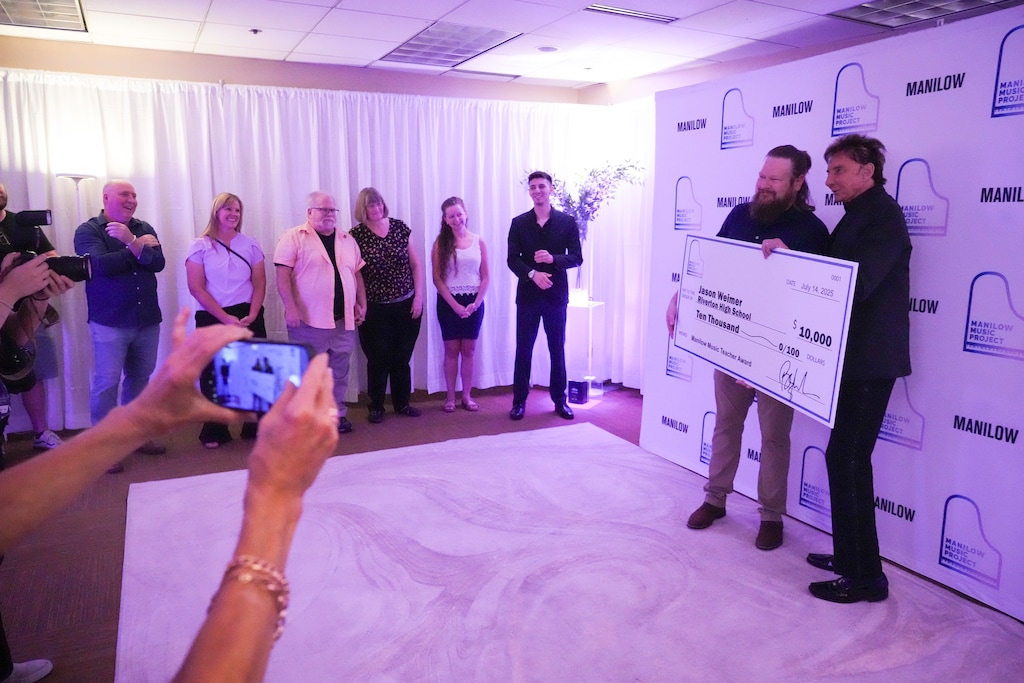 (Bethany Baker | The Salt Lake Tribune) Riverton High School's performing arts director Jason Weimer, second from right, poses for a photo with Barry Manilow as Weimer receives an award from the Manilow Music Project, an organization that supports local music programs, before Manilow's concert during his farewell tour at the Maverik Center in West Valley City on Monday, July 14, 2025.