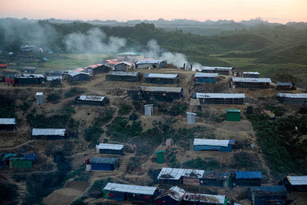 (A.M. Ahad | The Associated Press) Rohingya Muslims stand, as smoke emits from the Hakim Para refugee camp in Ukhiya, Bangladesh Monday, Nov. 13, 2017. More than 600,000 members of the Muslim minority have fled to Bangladesh since August, when Rohingya insurgents attacked Myanmar police and paramilitary posts, and security forces responded with a scorched-earth campaign against Rohingya villages.