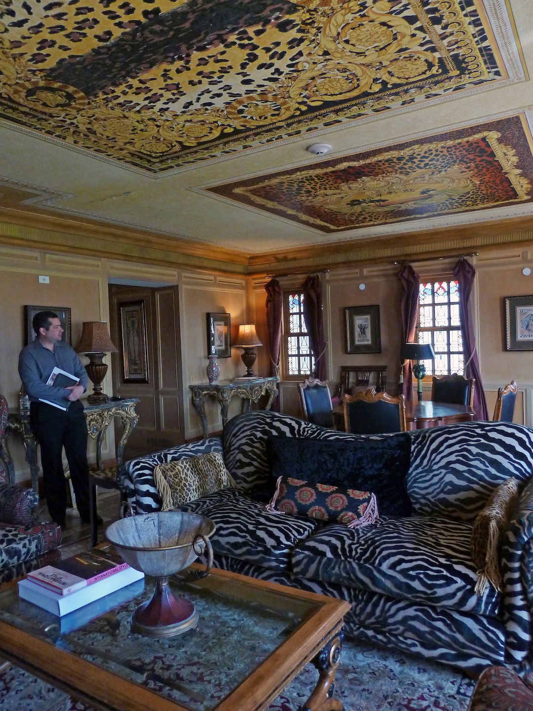 In this Tuesday, Dec. 26, 2017 photo, Reynaldo Ramirez, Victor Hotels director of sales, waits in the sitting room of the Signature Suite at The Villa Casa Casuarina in Miami Beach, Fla. The suite is one of 10 suites featuring frescos and other opulent artwork created by fashion designer Gianni Versace, who once used the property as a private home. (AP Photo/Jennifer Kay)