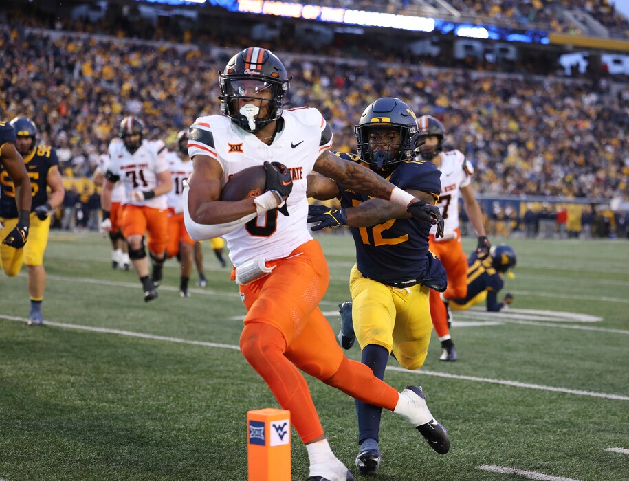 Oklahoma State's Ollie Gordon (0) carries the ball in for a rushing touchdown as West Virginia's Anthony Wilson (12) pursues during the second half of an NCAA college football game Saturday, Oct. 21, 2023, in Morgantown, W.Va. (AP Photo/Chris Jackson)