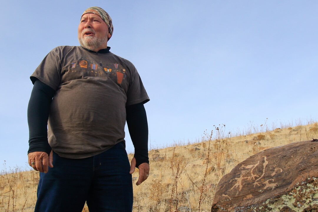 Steven Acerson, the president of the Utah Rock Art Research Association, looks out over the West Mountain area of Utah as he stands next to a rock with petroglyphs on Thursday, Feb. 8, 2018. (Evan Cobb/The Daily Herald via AP)
