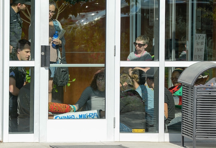 (Francisco Kjolseth  |  The Salt Lake Tribune)  Activists stage a protest against a private prison company with contracts to hold undocumented immigrants on Thursday, July 12, 2018, after locking themselves in the lobby at the headquarters of Management and Training Corporation in Centerville.