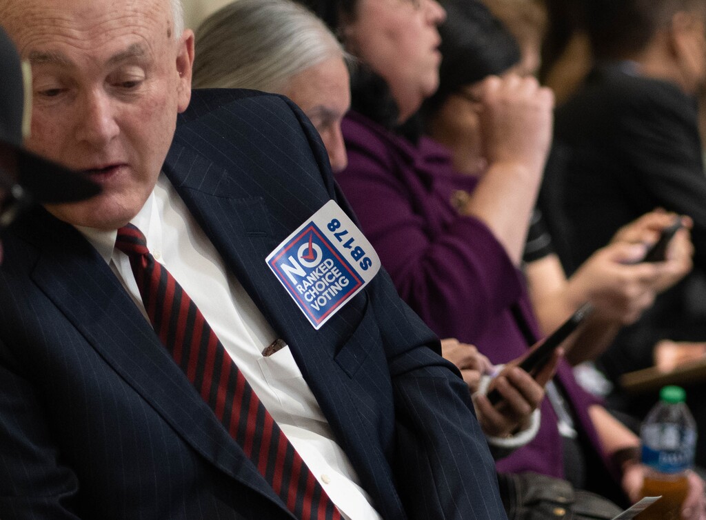 (Francisco Kjolseth | The Salt Lake Tribune) Opponents of a bill to expand the use of rank choice voting, distribute stickers to people attending a hearing on the the measure at the Utah Capitol on Wednesday, Feb. 9, 2022, before the bill was pulled from the agenda shortly before the meeting started.