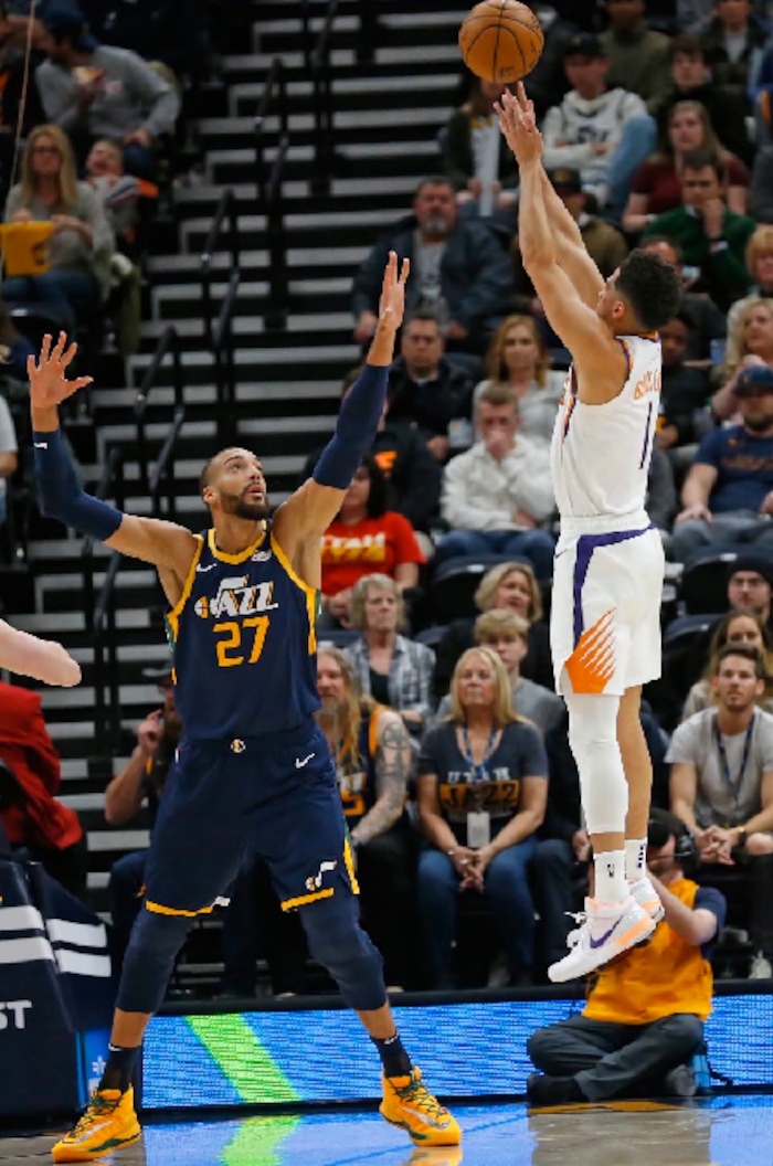Phoenix Suns guard Devin Booker (1) shoots as Utah Jazz center Rudy Gobert (27) defends in the first half during an NBA basketball game Monday, Feb. 24, 2020, in Salt Lake City. (AP Photo/Rick Bowmer)