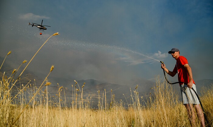 (Francisco Kjolseth  |  The Salt Lake Tribune)  Greg Robbins does his part in trying to add some moisture to tall brush behind his house as crews battle a grass fire in Tooele county being dubbed the Green Ravine fire as it burns on Tuesday, Sept. 3, 2019.