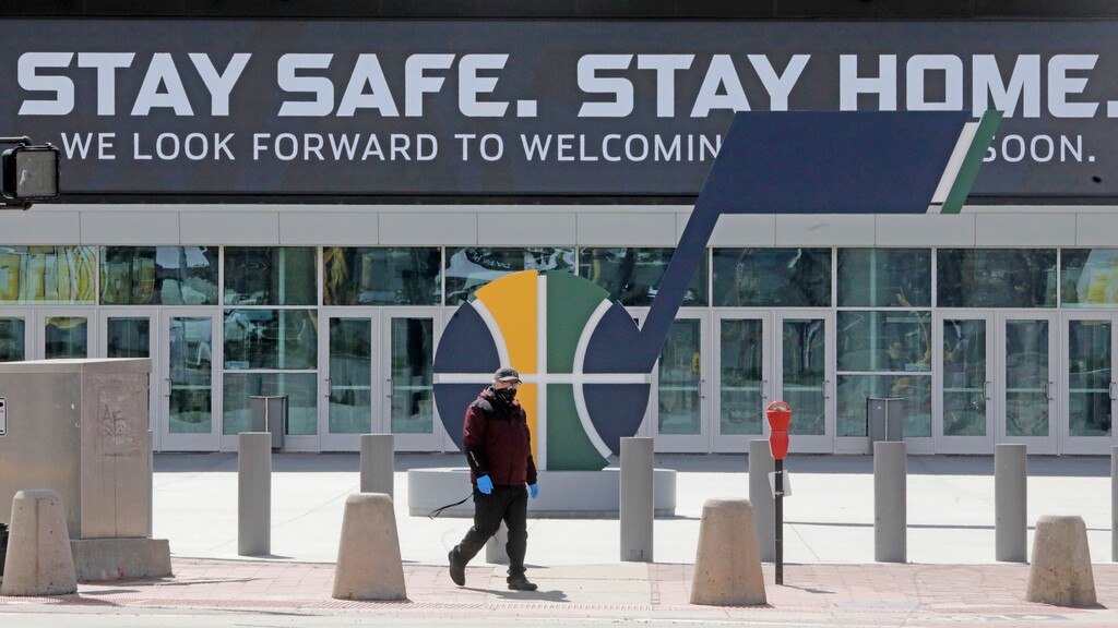 A man wears a masks as he walks past the Vivint Smart Home Arena Monday, April 13, 2020, in Salt Lake City. Utah Gov. Gary Herbert is extending his voluntary directive telling people to stay home except for essential errands through the end of April. He is also encouraging people to wear masks when at stores and other businesses to prevent the spread of the virus. (AP Photo/Rick Bowmer)