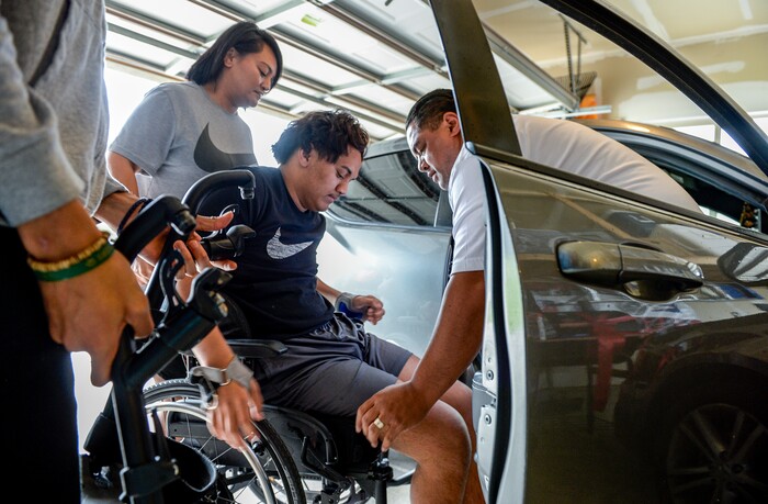 (Leah Hogsten  |  The Salt Lake Tribune) l-r After his daily physical therapy session, Stak is helped into his wheelchair at home by his mother Grace and father Skee Afatasi. Audrick “Stak” Afatasi is fighting to regain movement in his lower body after being paralyzed at a trampoline park on March 15, 2019.