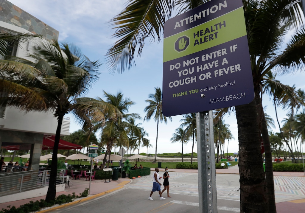 (Wilfredo Lee | AP file photo)

In this June 22 photo a couple walks past a sign asking people not to visit Miami Beach, Florida's famed South Beach if they have a cough or fever. An Associated Press analysis of coronavirus case data shows the virus has moved, and is spreading quickly, into Republican areas, a new path with broad potential political ramifications.