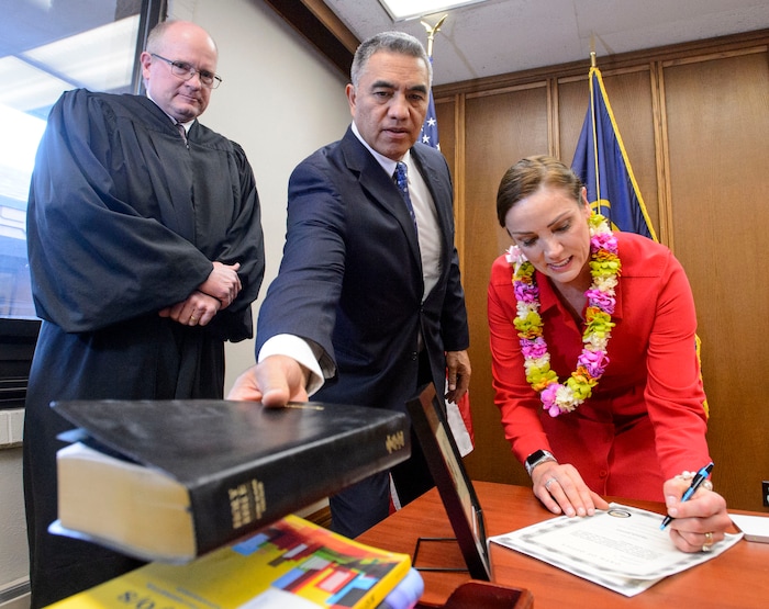 (Steve Griffin | The Salt Lake Tribune) Joined by her husband Steve Kaufusi, center, Michelle Kaufusi signs paper work after taking the Oath of Office, administered by Judge Vernon Romeny, left, as she becomes the first female mayor in Provo city's history. The small private ceremony was held in the Mayor's Office in Provo Tuesday January 2, 2018. A public Inauguration Ceremony for Mayor Kaufusi will be held at the Provo Library on January 18, 2018.