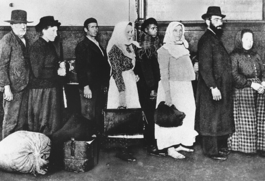 (AP) In this undated file photo, immigrants who arrived at Ellis Island in New York wait in line to begin immigration proceedings.