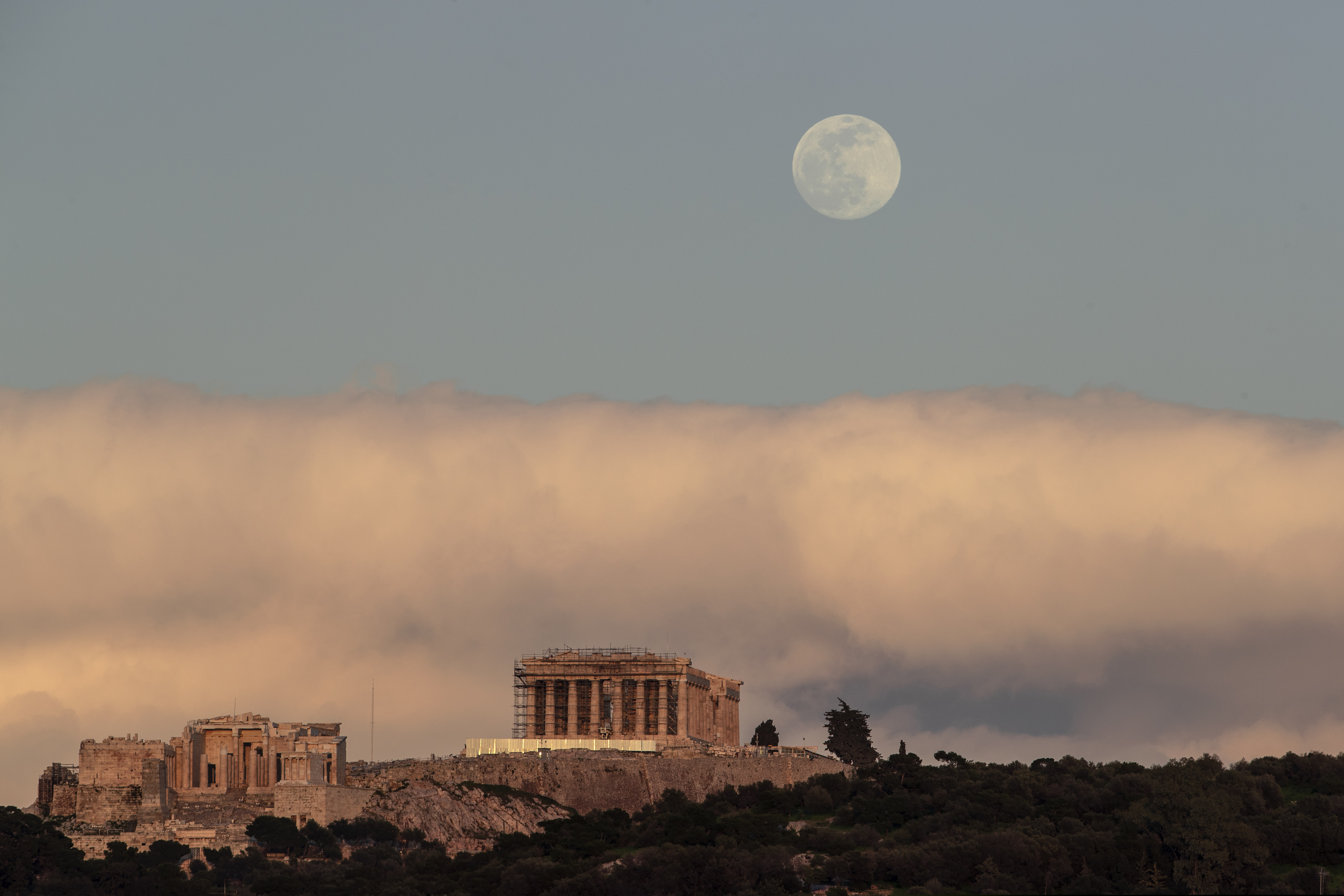 The moon rises behind the ancient Acropolis hill with the 500 BC Parthenon temple in Athens, on Saturday, Feb. 8, 2020. (AP Photo/Petros Giannakouris)