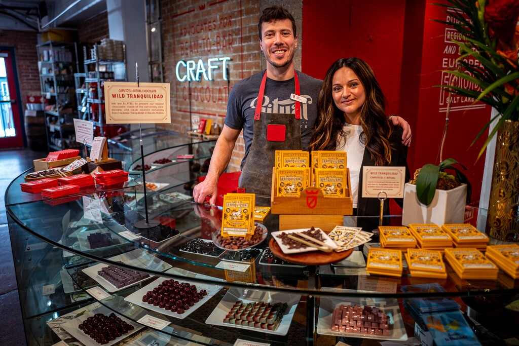 (Trent Nelson | The Salt Lake Tribune) Matt and Yelena Caputo, standing with a display of Wild Tranquilidad chocolate bars at Caputo's Market & Deli in downtown Salt Lake City on Thursday, May 11, 2023. The bars, produced by Caputo's and Ritual Chocolate, are made with wild cacao harvested in Bolivia.