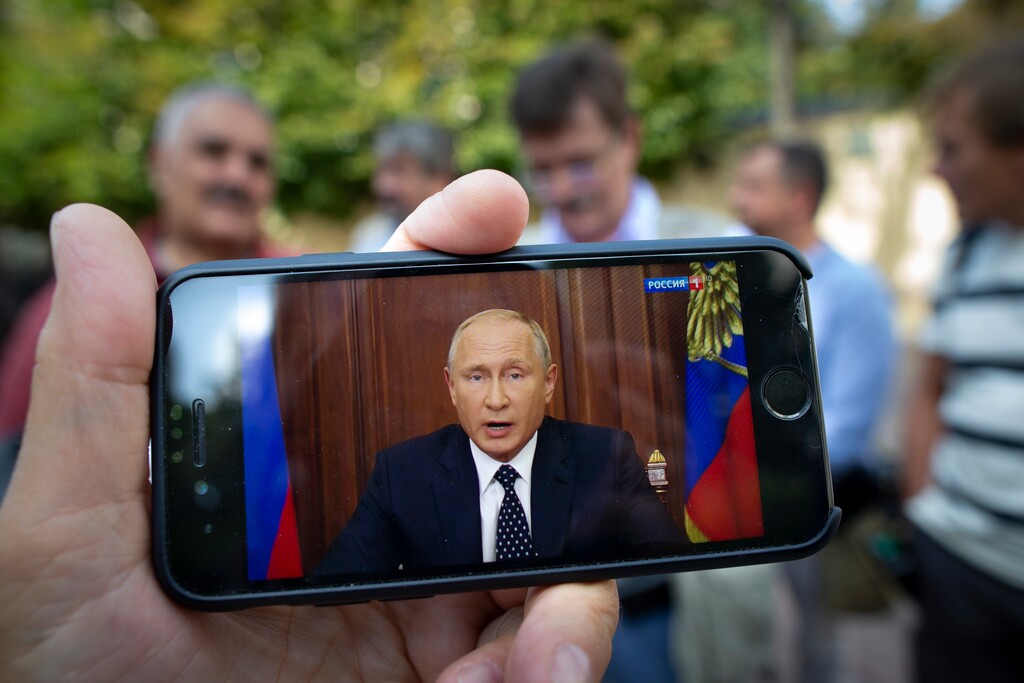 (Alexander Zemlianichenko | The Associated Press) People stand in a street in Moscow, Russia, Wednesday, Aug. 29, 2018, as Russian President Vladimir Putin addresses on state TV. Putin in a televised address Wednesday said without raising the retirement age Russia's pension system "would crack and eventually collapse." He offered concessions to the reform, saying that women's retirement age should increase from 55 to 60 years, lower than had proposed.