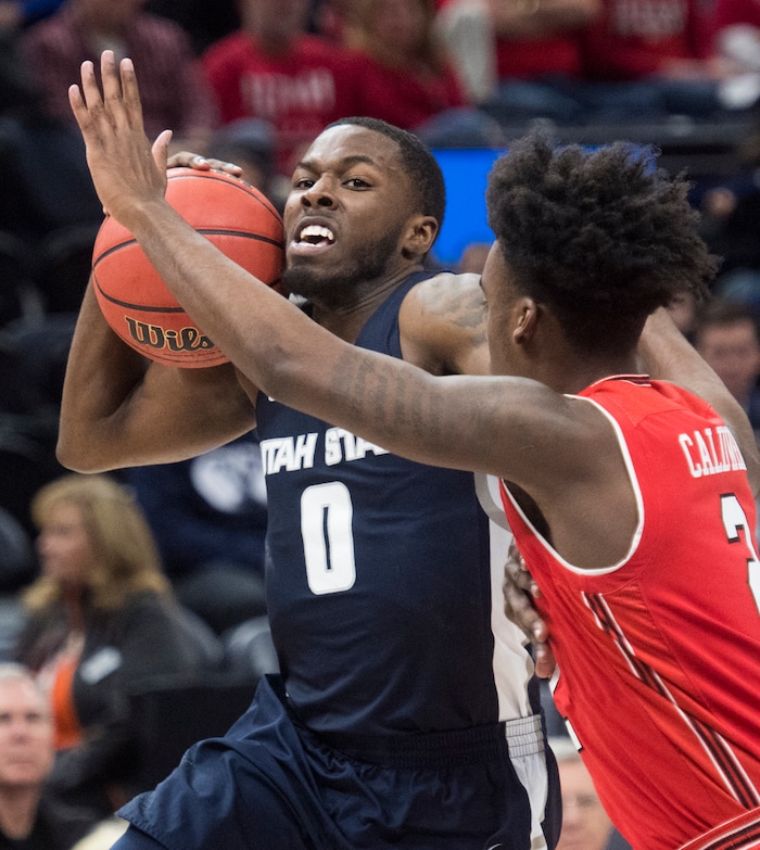 (Rick Egan  |  The Salt Lake Tribune) Utah State Aggies guard DeAngelo Isby (0) takes the ball inside, as Utah Utes guard Kolbe Caldwell (2) defends, in Beehive Classic basketball action at the Vivint SmartHome Arena, Saturday, December 9, 2017.