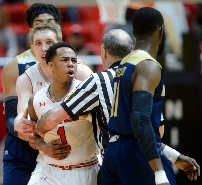 (Steve Griffin  |  The Salt Lake Tribune)  Utah Utes guard Justin Bibbins (1) is held back by Utah Utes forward Tyler Rawson (21) and the ref after he was fouled hard by UC Davis Aggies guard Michael Onyebalu (31) during the men's NIT basketball game at the Huntsman Center in Salt Lake City Wednesday March 14, 2018. Onyebalu was called for a flagrant 1 foul on the play.